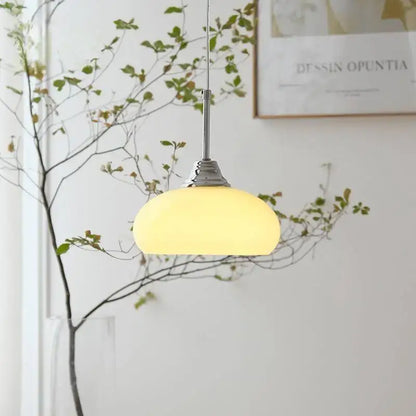 Decorbites cream glass pendant light featuring warm yellow translucent glass and chrome hardware for dining rooms