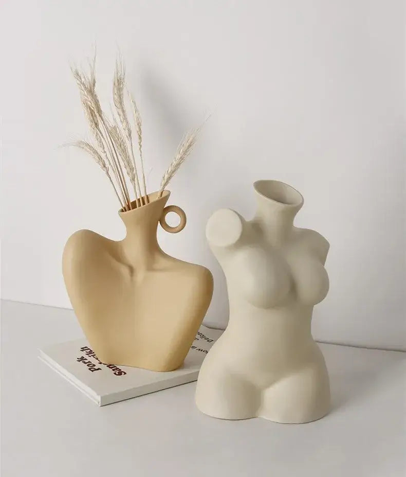 Beige ceramic human vase shaped like a female torso with circular handle holding dried wheat stalks for home decor