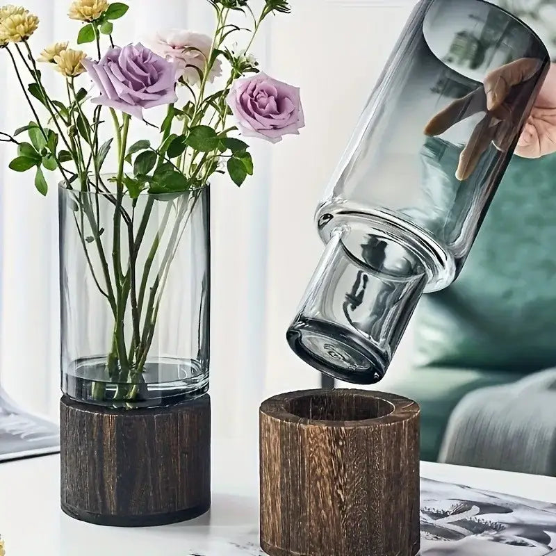 Tall clear creative retro glass vase with dark wood base holding purple and yellow roses for living room decor