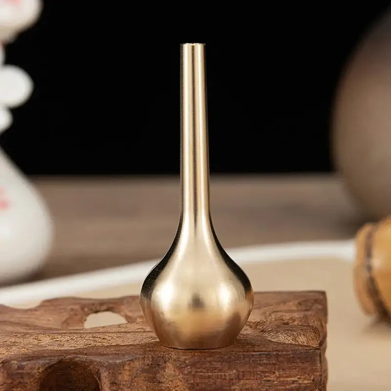 A sleek brass-colored plastic flower vase with a slender neck and rounded base for floral arrangements by DecorBites™