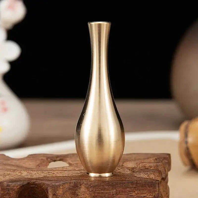 A sleek slender brass-colored plastic flower vase with a smooth reflective surface for floral arrangements