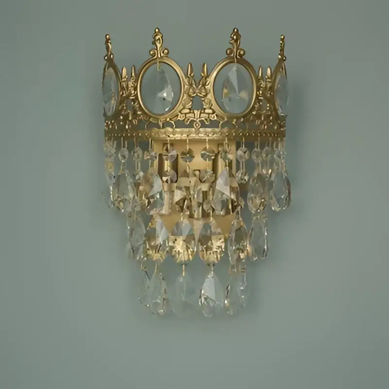 Gold-toned decorbites crown crystal wall sconce with clear crystal droplets for elegant bedroom lighting