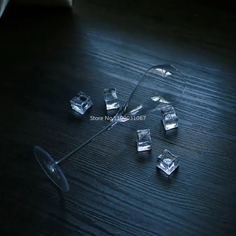 A decorbites crystal champagne flute with a long stem and wide bowl lies on its side among clear ice cubes