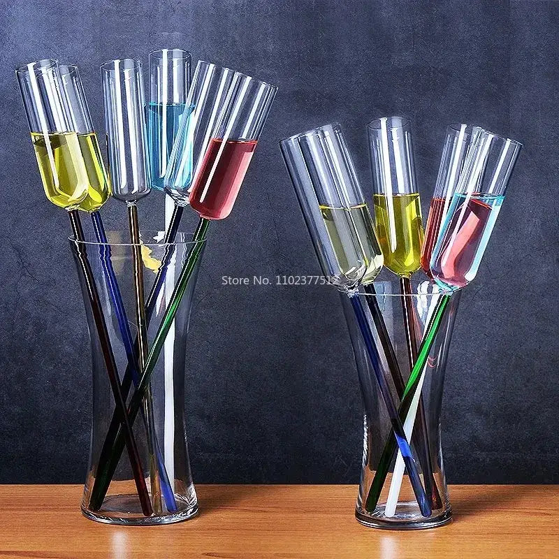 Two clear glass vases holding colorful decorbites crystal champagne wine glasses filled with liquid on a wooden surface