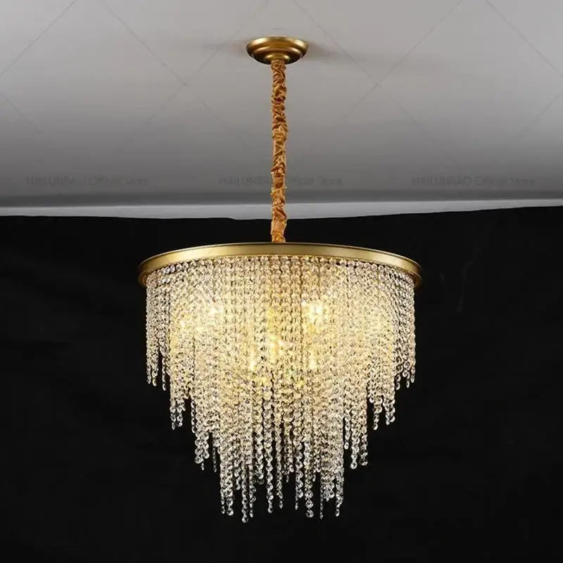 Gold-toned decorbites crystal chandelier with cascading clear crystal droplets on a circular brass frame for living rooms