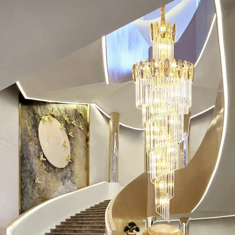 Decorbites crystal chandelier with cascading crystal prisms and gold-toned accents above curved staircase lighting