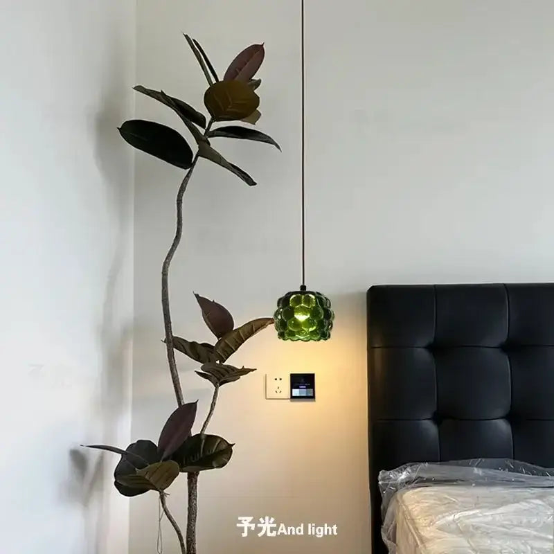 Green faceted glass pendant light with black cord hanging beside plant in decorbites crystal chandelier for store cashier area