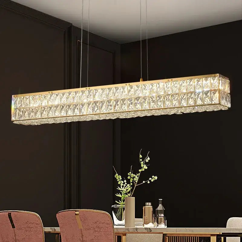 Rectangular decorbites crystal chandelier with gold-toned frame and faceted glass panels above dining table