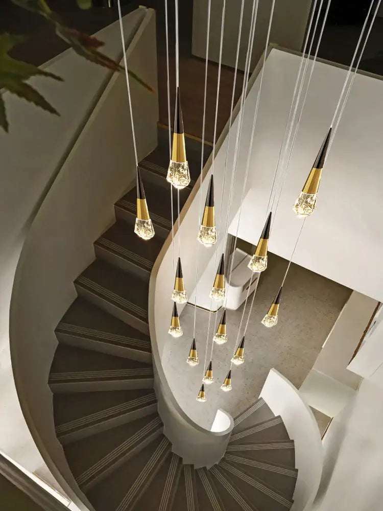 A decorbites crystal chandelier led with gold-toned cone fixtures suspended above a curved staircase for elegant spaces