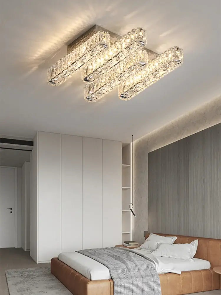 Modern rectangular decorbites crystal chandelier with three horizontal faceted glass bars refracting warm light