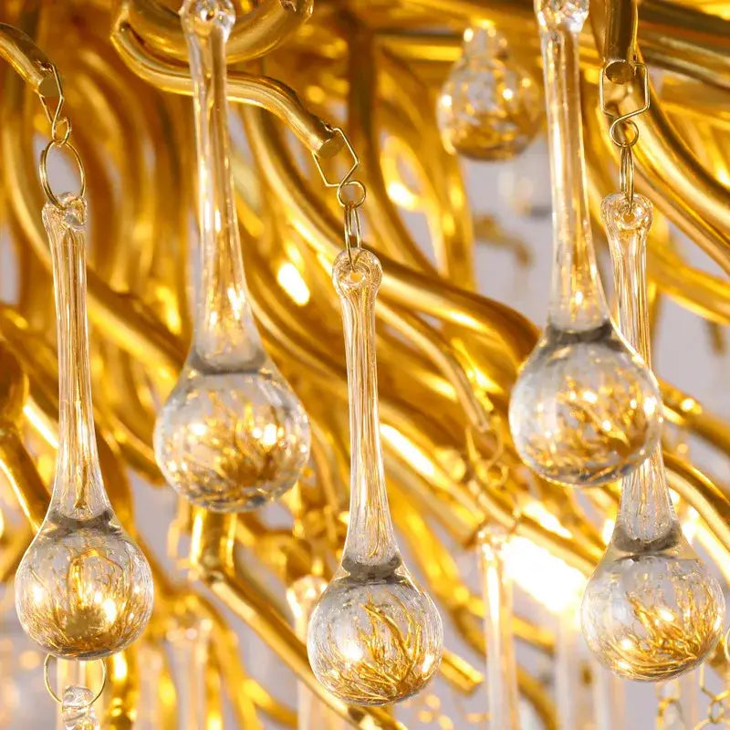 Golden decorbites crystal chandelier with clear glass teardrop pendants and intricate gold-toned metalwork lighting fixture