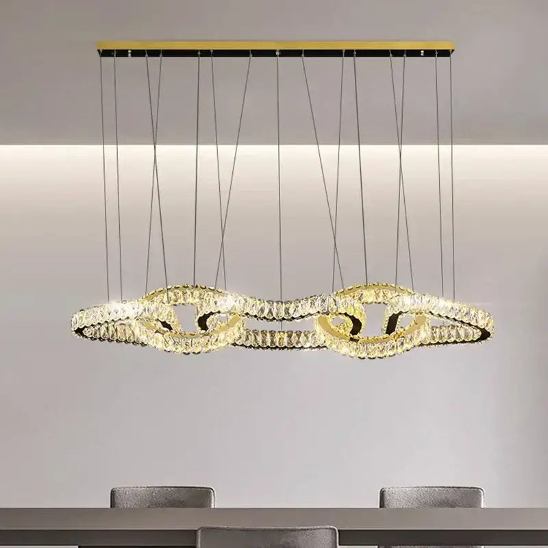 Gold-toned DecorBites crystal chandelier with interlocking crystal rings suspended by thin cables for luxury living room lighting