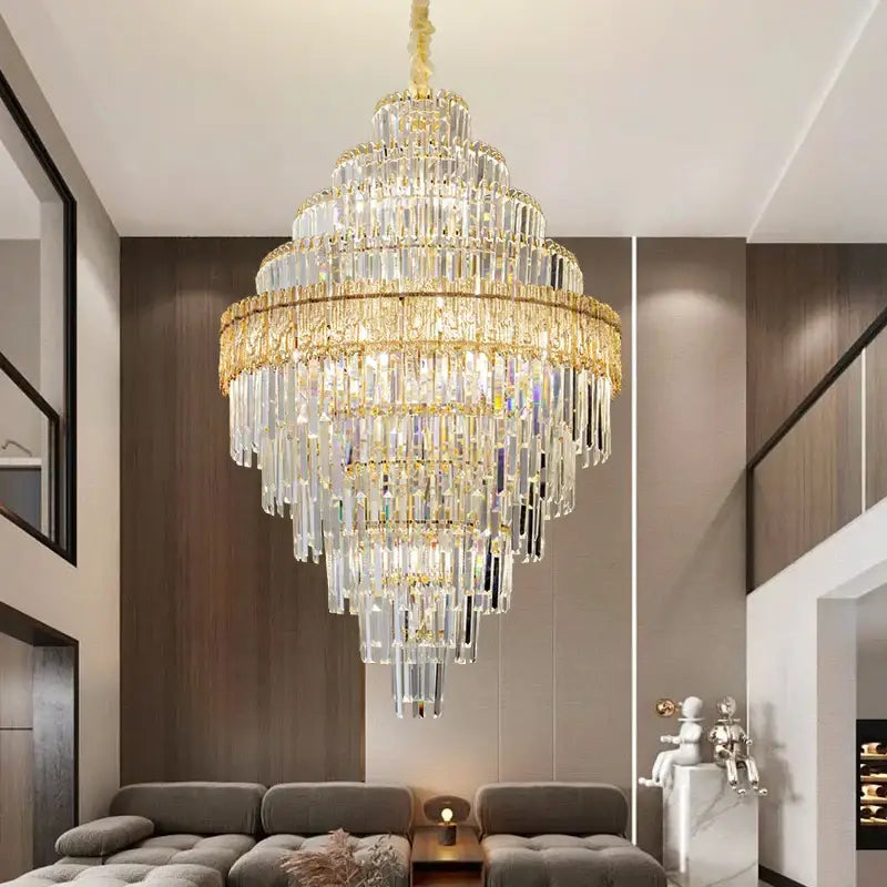 A multi-tiered decorbites crystal chandelier with gold-toned metal and cascading clear glass prisms for elegant lighting