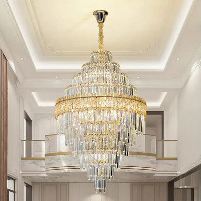 A multi-tiered decorbites crystal chandelier with gold-toned metal and clear prisms for elegant living room lighting