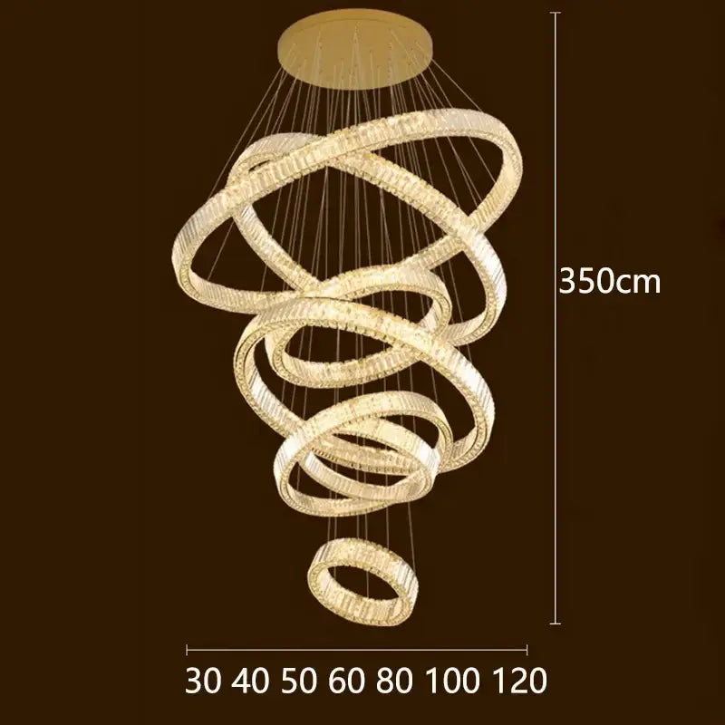 A modern 350cm tall decorbites crystal chandelier with interlocking rings and clear crystals emitting warm golden light