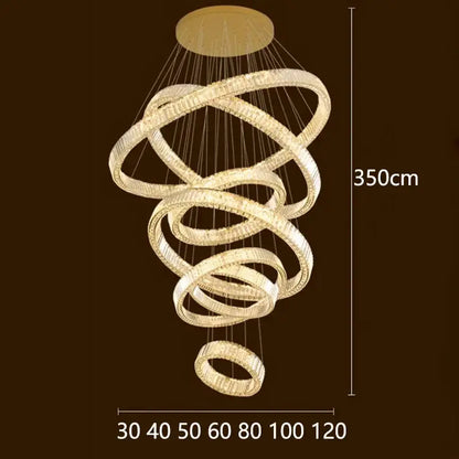 A modern 350cm tall decorbites crystal chandelier with interlocking rings and clear crystals emitting warm golden light