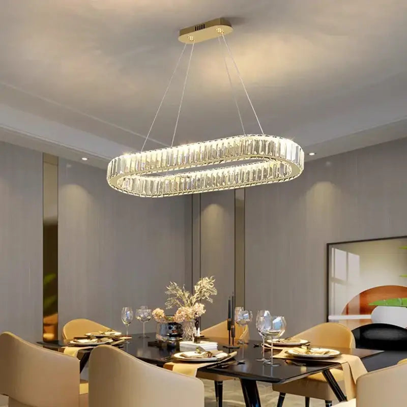 A modern oval-shaped decorbites crystal chandelier with gold-toned ceiling mount and clear faceted glass elements