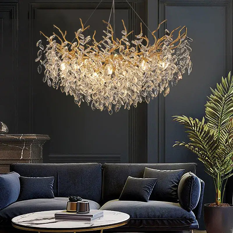 Gold-toned decorbites crystal chandelier with intricate crystal leaves hanging above dark blue velvet sofa