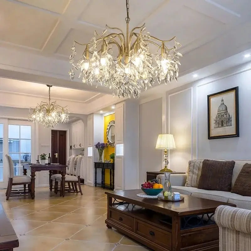 Gold-toned decorbites crystal chandelier with crystal droplets on an ornate metal frame for living room and bedroom lighting