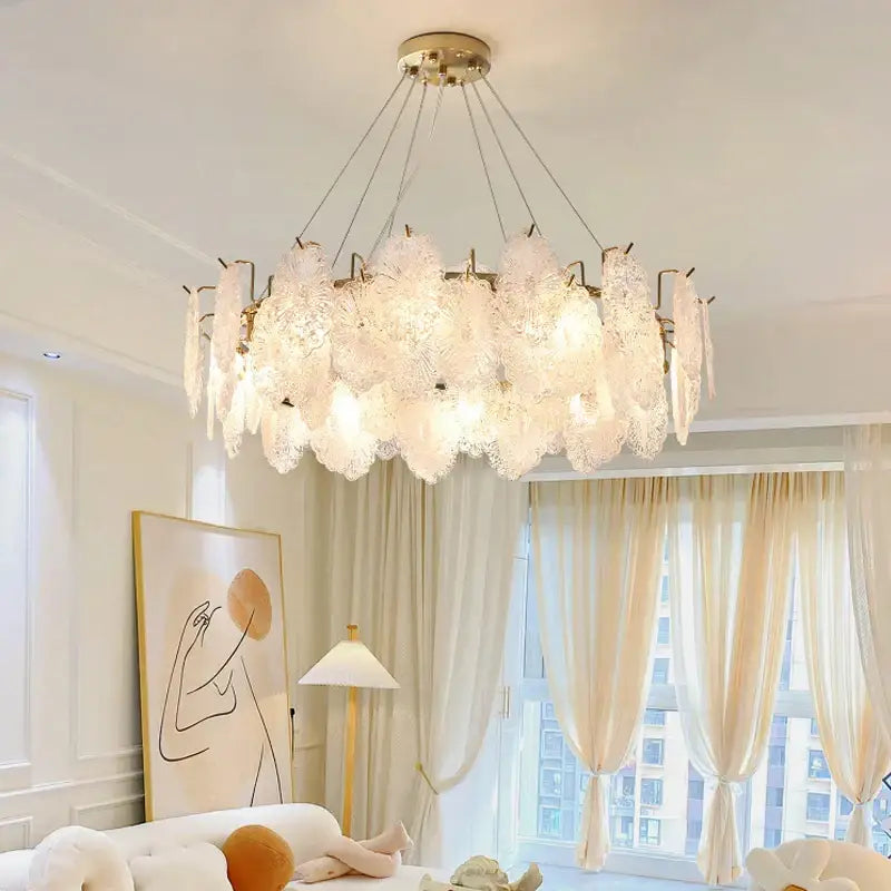 A delicate translucent white decorbites crystal chandelier with a gold-toned ceiling fixture and hanging chains for living room