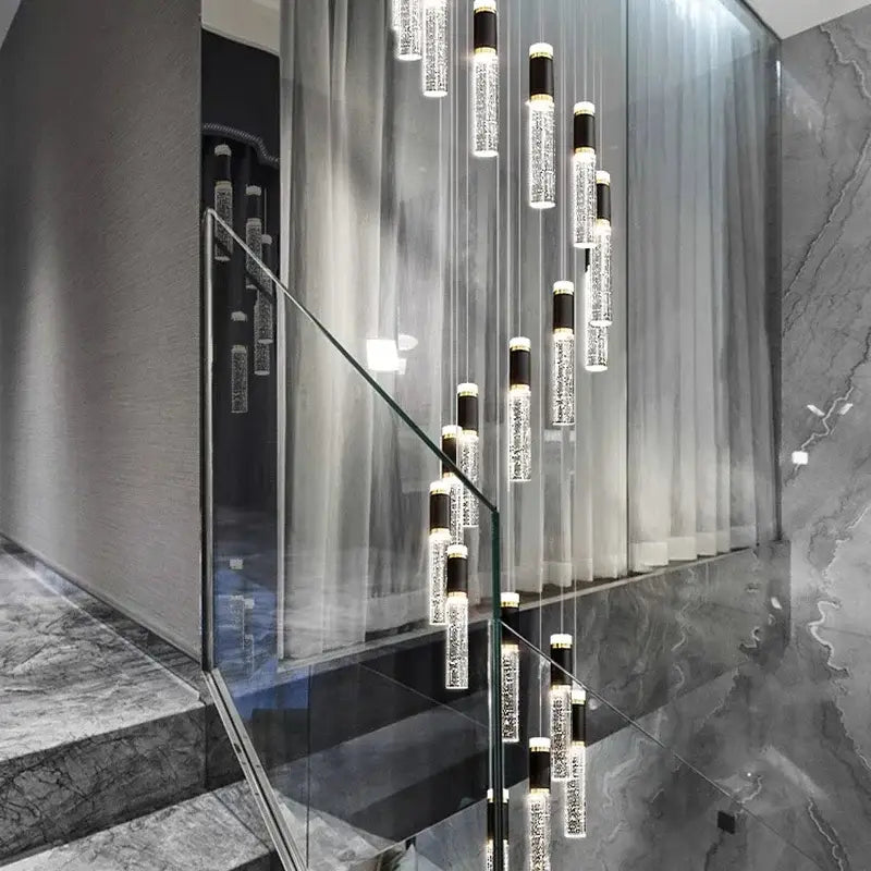 Modern decorbites crystal chandelier with clear glass cylinders and black accents in a contemporary staircase setting