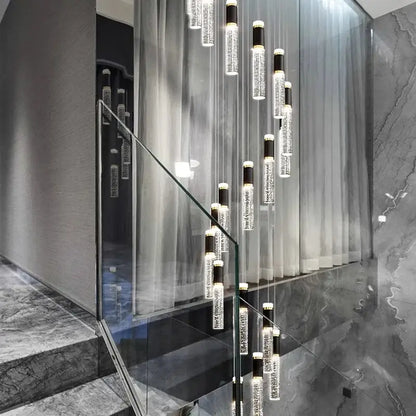 Modern decorbites crystal chandelier with clear glass cylinders and black accents in a contemporary staircase setting