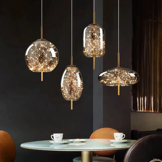 Three modern decorbites crystal chandelier pendant lights with clear glass globes and warm LED fairy lights above a table