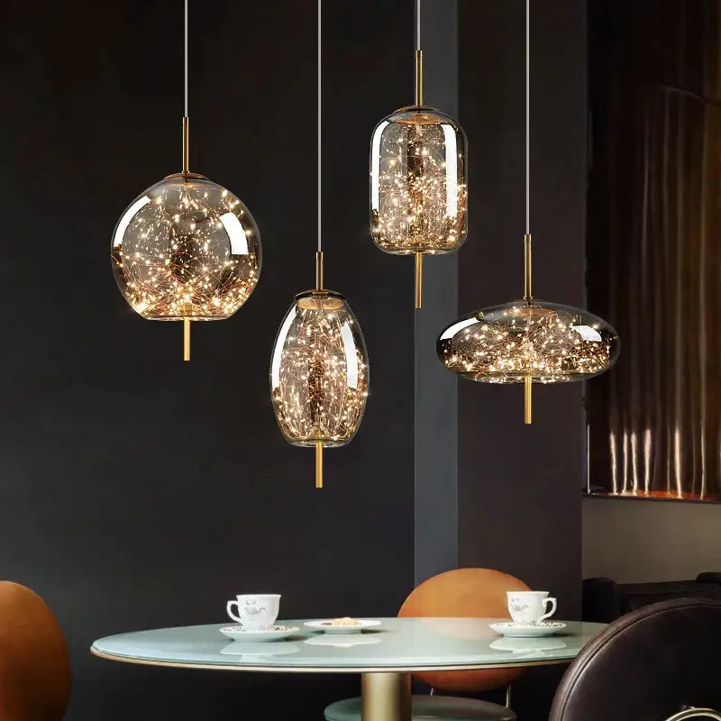 Three modern decorbites crystal chandelier pendant lights with clear glass globes and warm LED fairy lights above a table