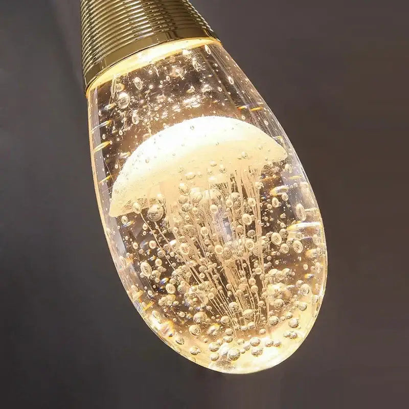 A golden-toned teardrop decorbites crystal led chandelier with clear glass and illuminated jellyfish design for dining room