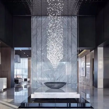 A decorbites crystal led chandelier with clear faceted crystals above a dark gray stone bowl on a white marble pedestal