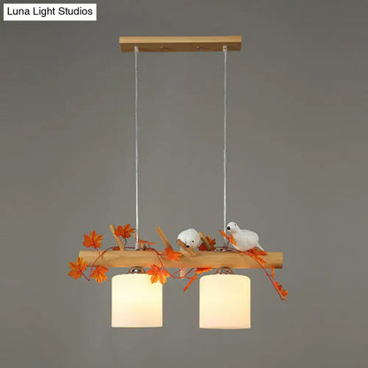 Rustic wooden pendant light with two warm cylindrical shades and resin bird deco on a natural wood branch for country style