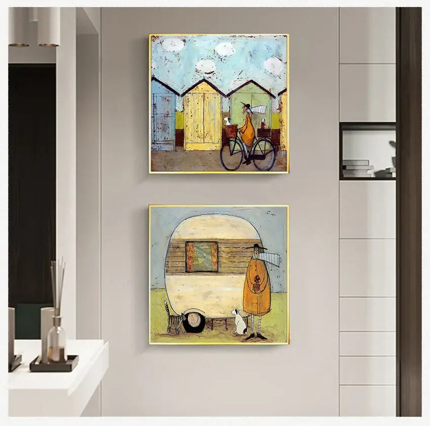 Two square-framed whimsical canvas wall art featuring a cyclist and orange-clad figure by a vintage camper trailer