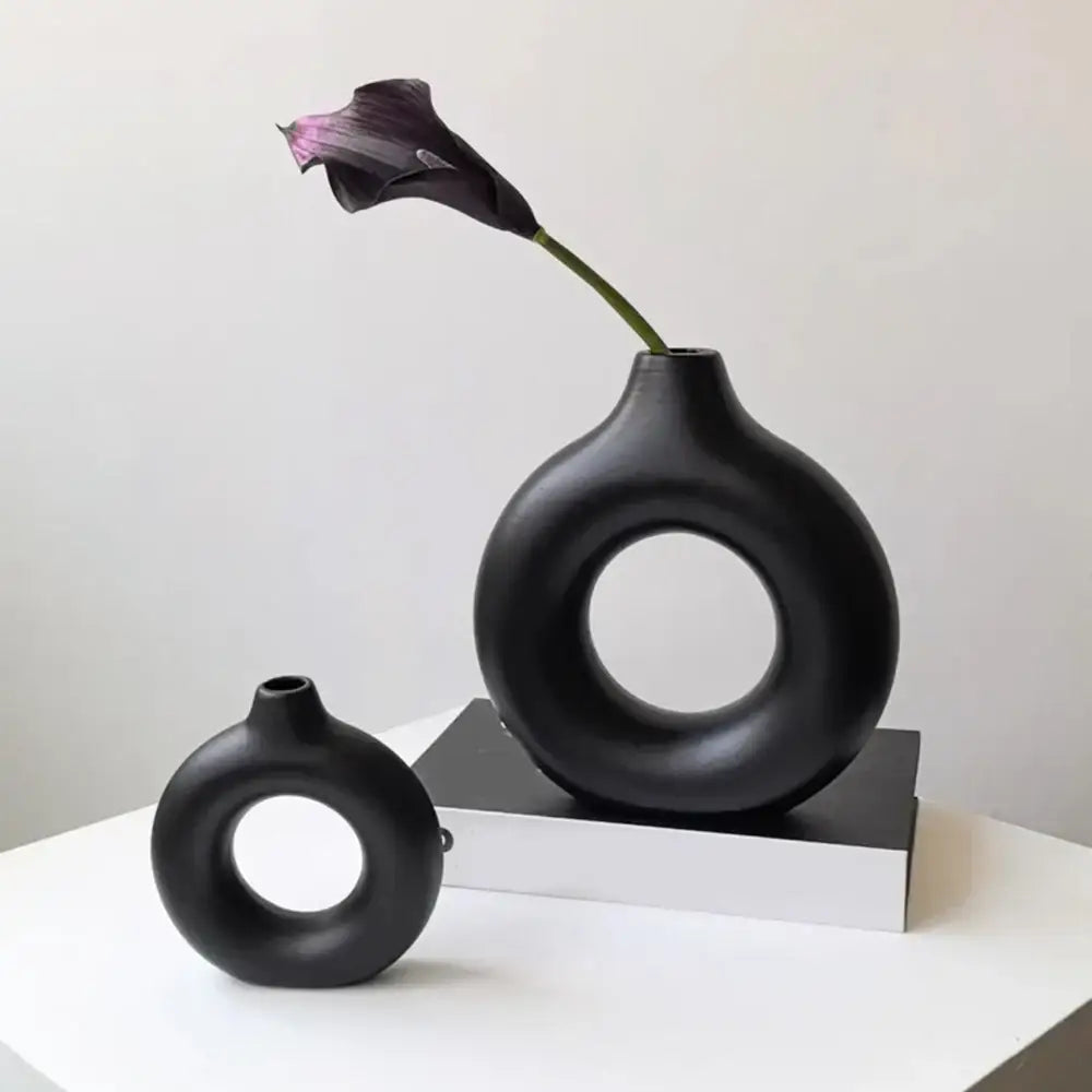 DecorBites™ black ceramic donut shape flower vase holding a single dark purple calla lily in a minimalist style