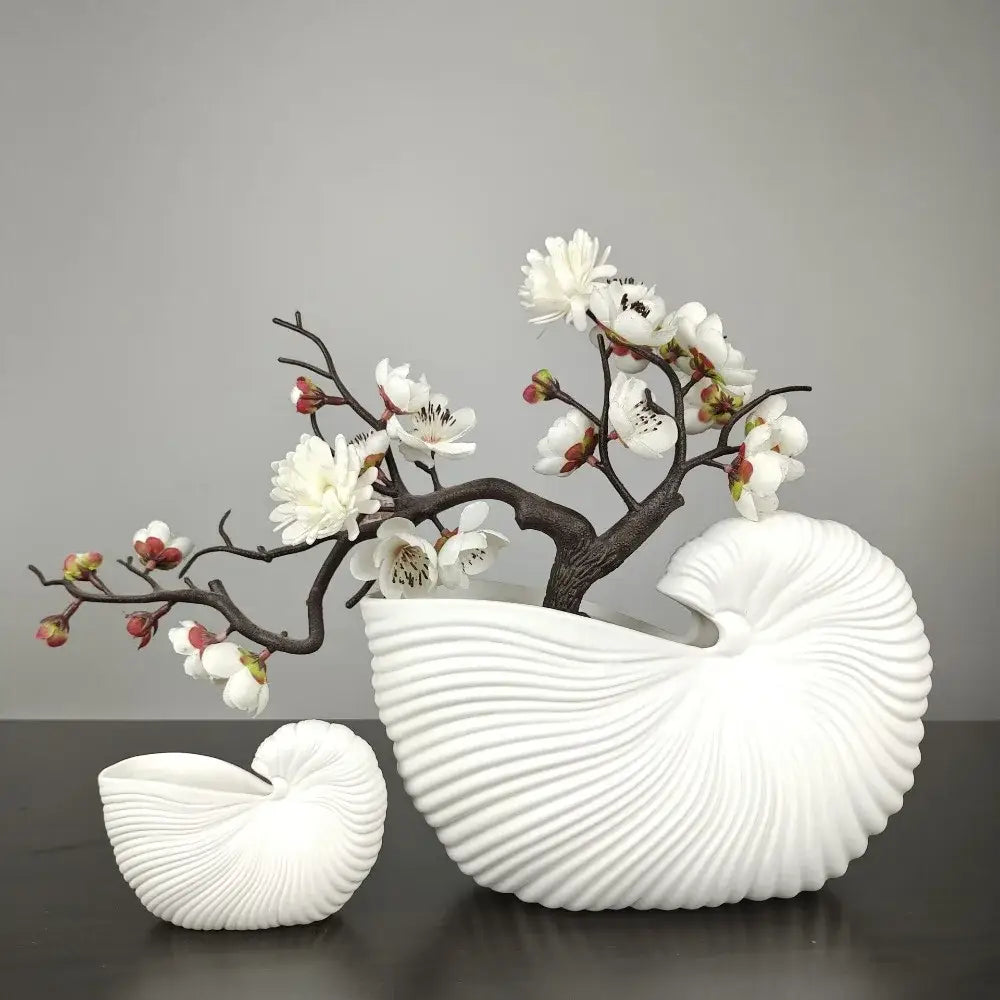 DecorBites™ elegant ceramic vase in white shell conch design with ribbed texture holding artificial white blossoms