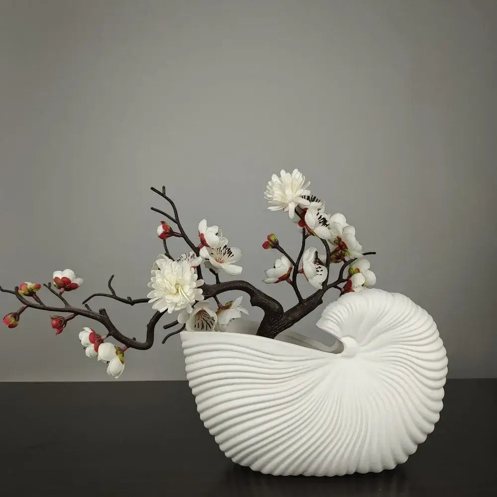 Decorbites™ elegant ceramic vase shaped like a white shell conch holding dark brown branches with white and pink blossoms