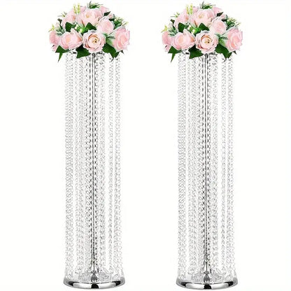 Two tall crystal chandeliers with cascading beads and pink roses in elegant metal vases for wedding decor