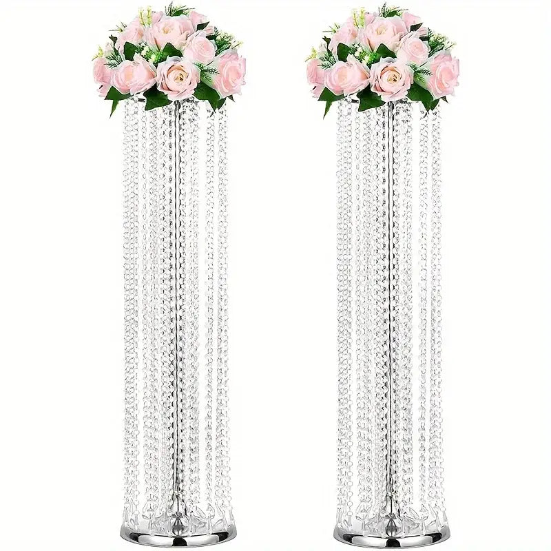 Two tall crystal chandeliers with cascading beads and pink roses in elegant metal vases for wedding decor