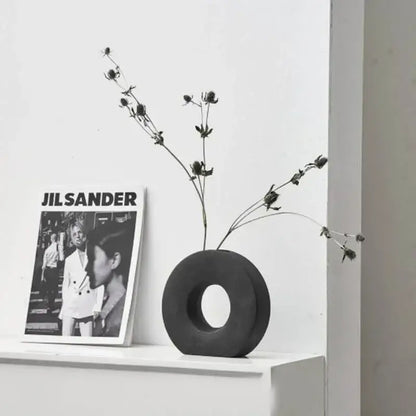 Black circular donut flower vase with central hole holding dried flowers for elegant nordic home decor