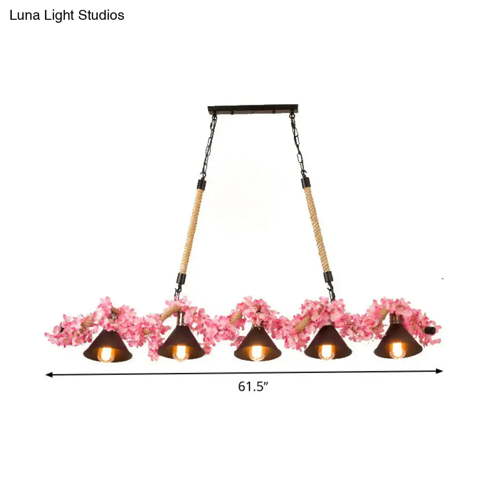 A rustic five-light factory conical island pendant light with dark metal shades pink floral accents and rope-wrapped chains