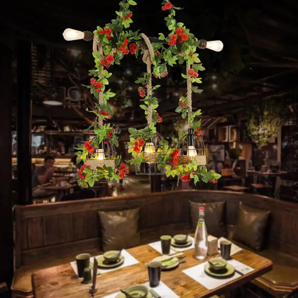 Rustic black metal island light pendant with five Edison bulbs, rope detail, and red roses draped over birdcages