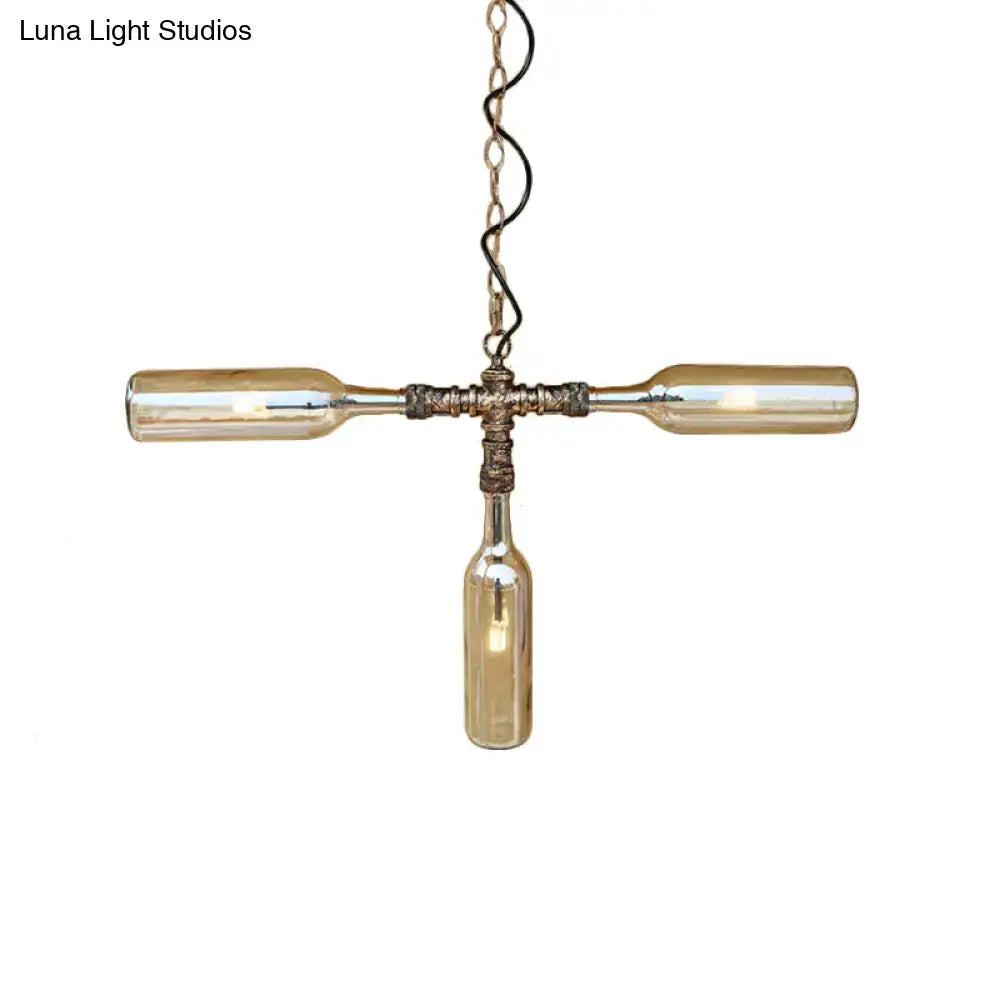A rustic cross-shaped pendant light with three amber glass bottles in aged silver black for farmhouse decor