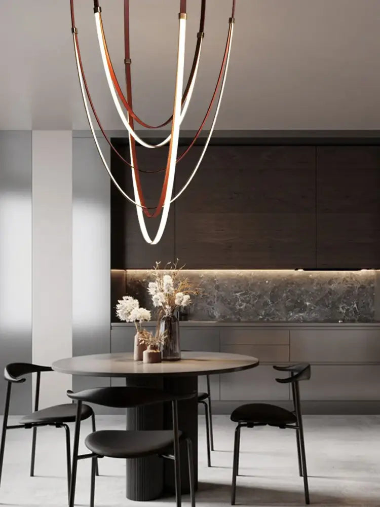 A modern led chandelier with curved white and brown leather belt bands for elegant living room lighting by DecorBites