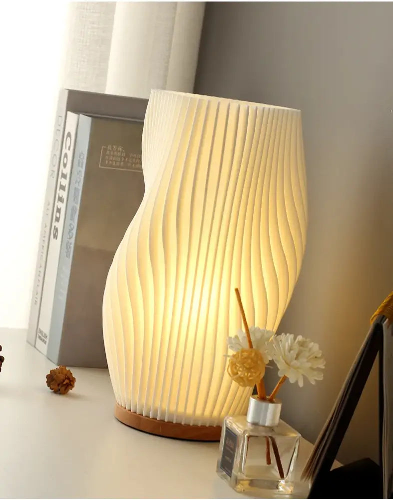 A french cream style desk lamp with a ribbed off-white translucent shade and wooden base creating a warm ambiance