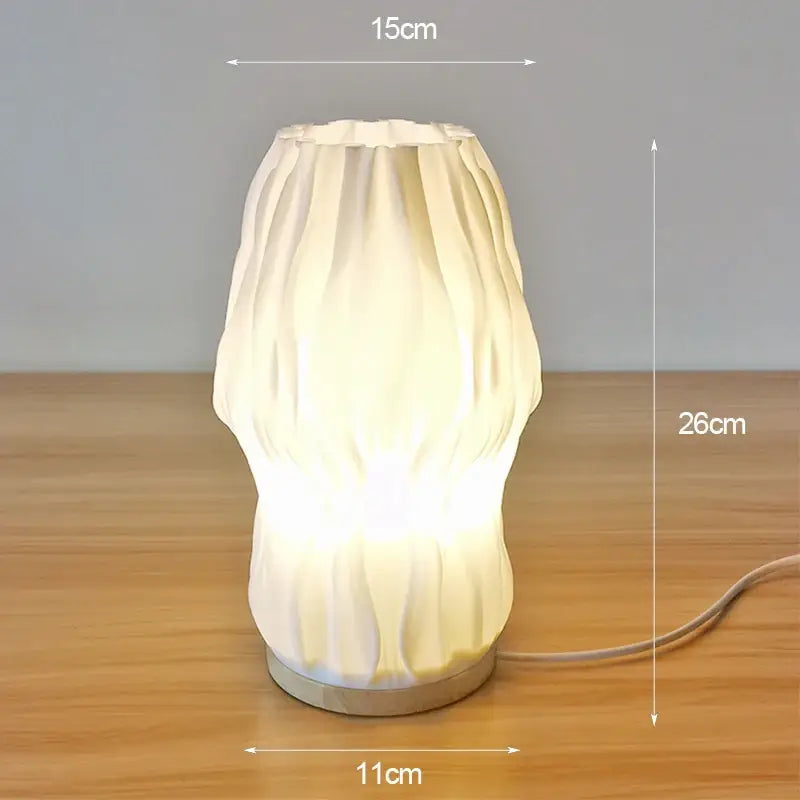 Cream-colored ribbed ceramic french cream style desk lamp with glowing base and metallic foot for bedside or study use
