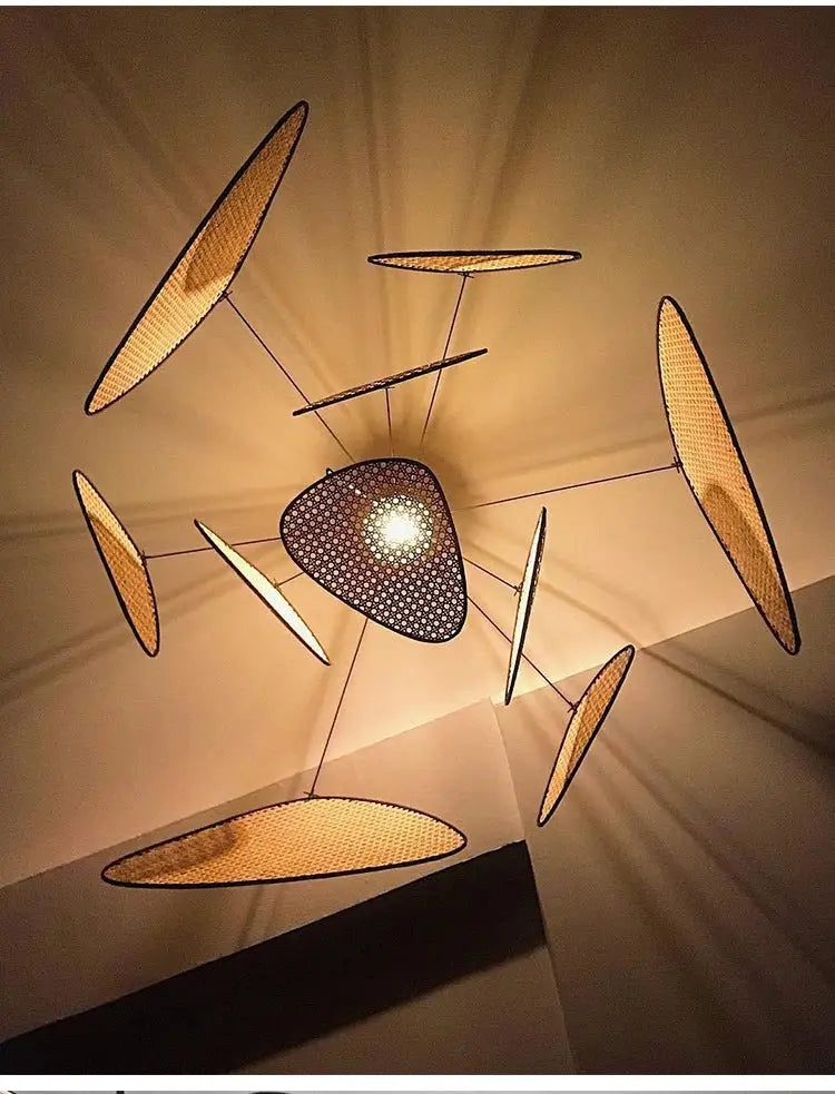 A modern french design rattan chandelier with a black perforated disc and golden-brown woven panels for home lighting