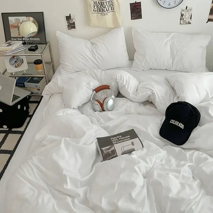 Silver and brown over-ear headphones resting on a white bedspread with decorbites fresh solid color cotton quilt set