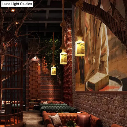 Warmly glowing frosted white glass hanging lamps shaped like black wine bottles with thick rope suspension for restaurants