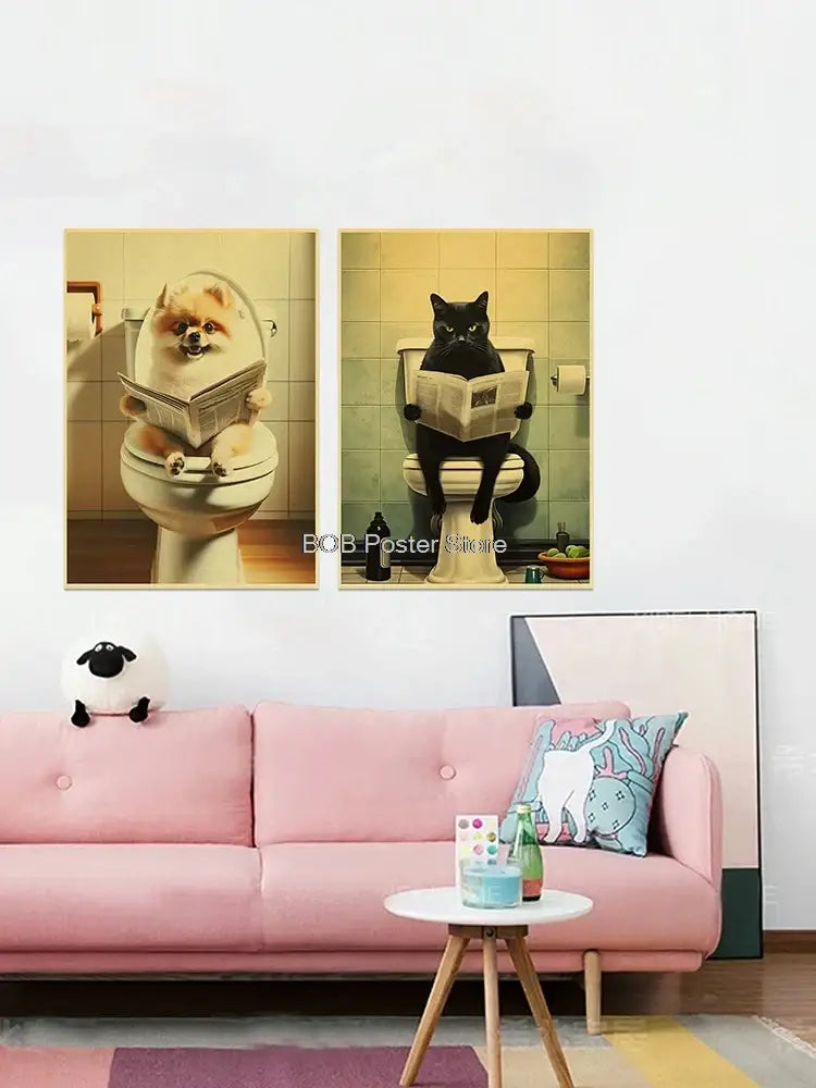 Two framed vintage-style animal bathroom posters featuring a pomeranian and black cat reading newspapers above a pink sofa