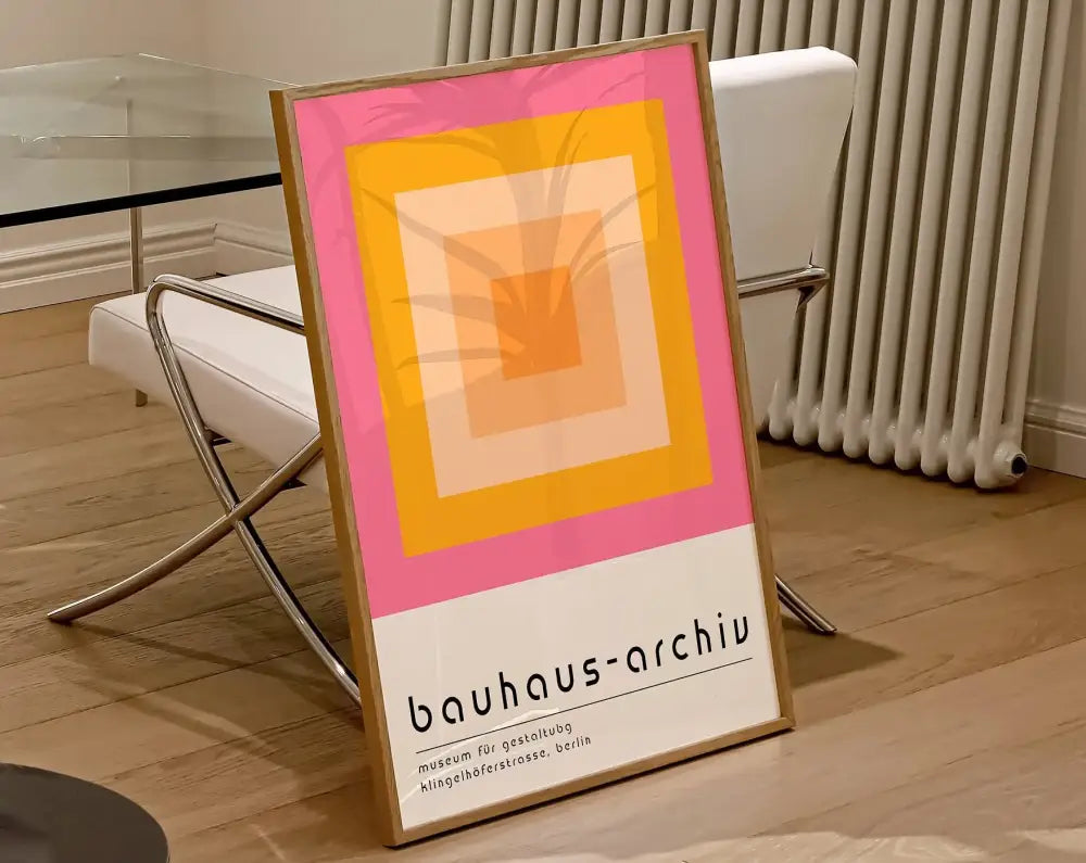 A framed canvas poster featuring geometric bauhaus concentric squares in pink yellow and orange hues on white background