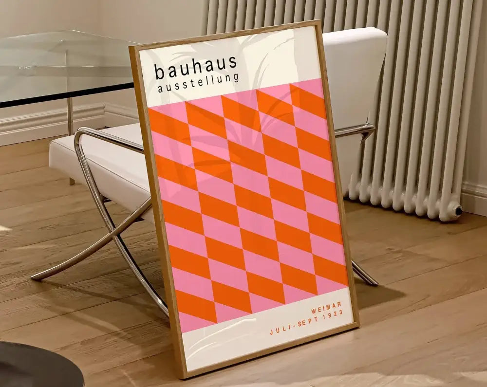 A framed DecorBites™ geometric canvas poster featuring a bold orange and pink diamond pattern in a light wood frame